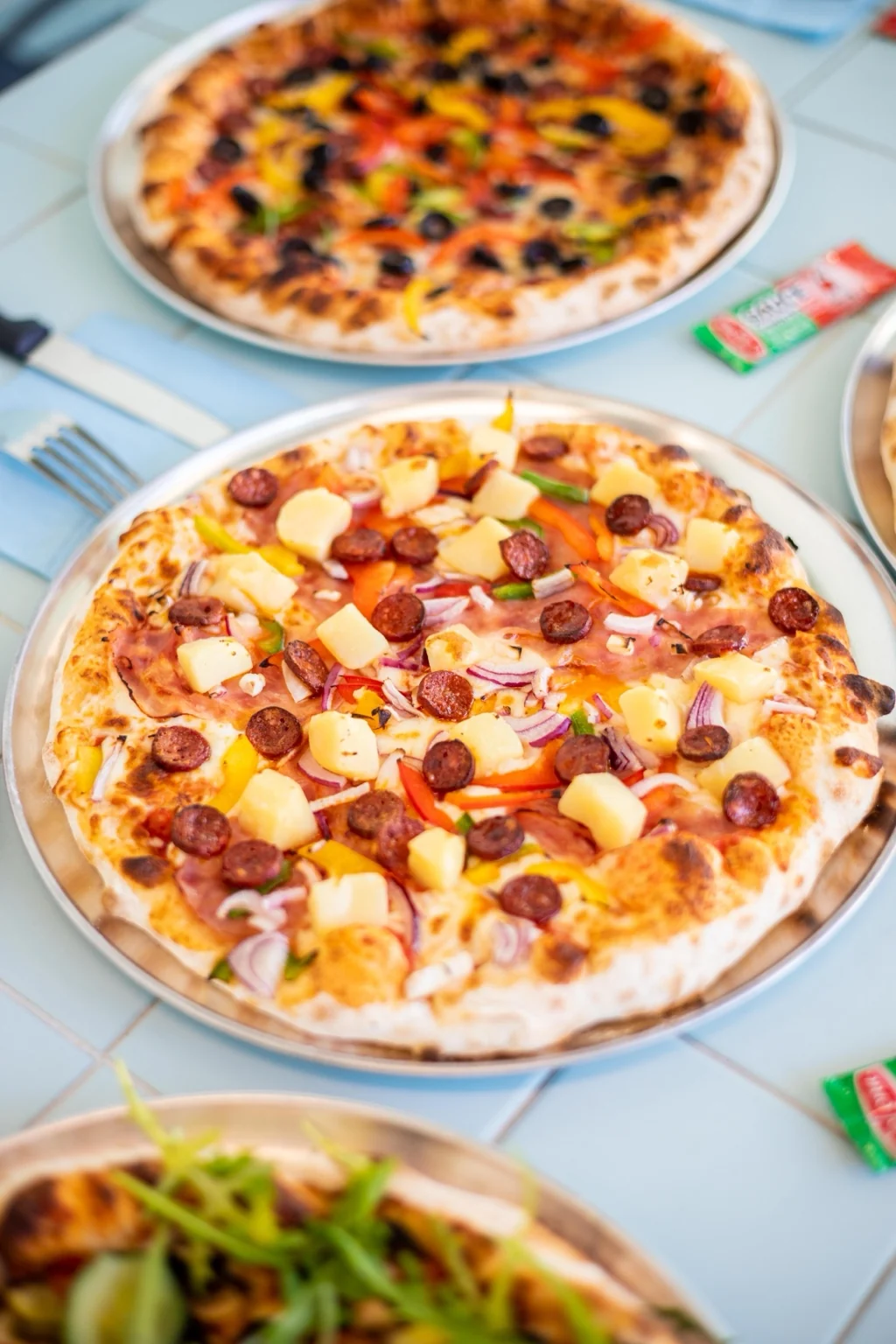 Pizzas FRICHE bien garnies, servies sur les tables carrelées du restaurant